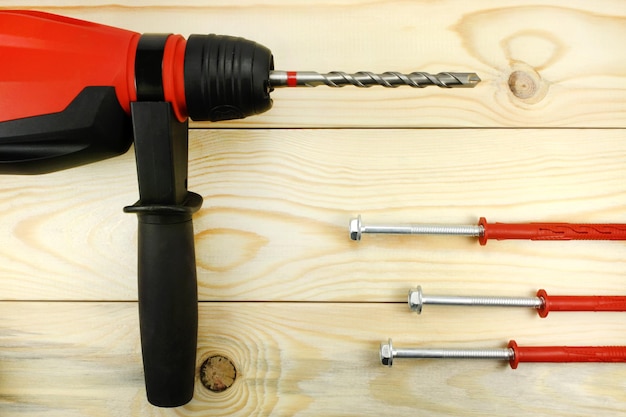 Hammer drill with anchors on wooden table