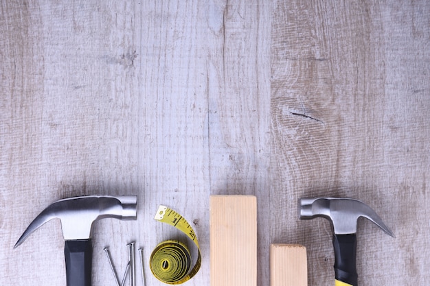 Hammer iron,centimeter tape and nails on wooden table