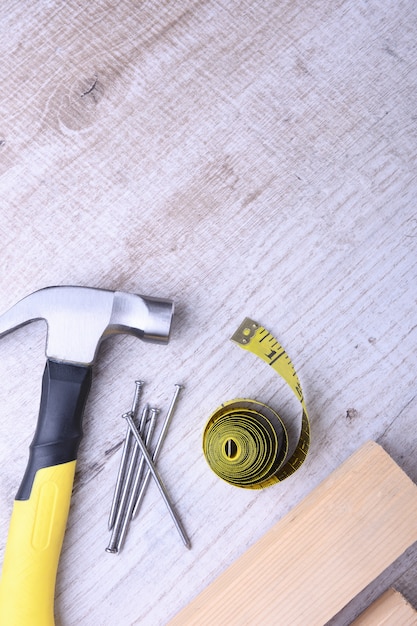 Photo hammer iron,centimeter tape and nails on wooden table