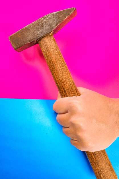 hammer for repair in hand on a colorful or  pink and blue space. repair or tools concept