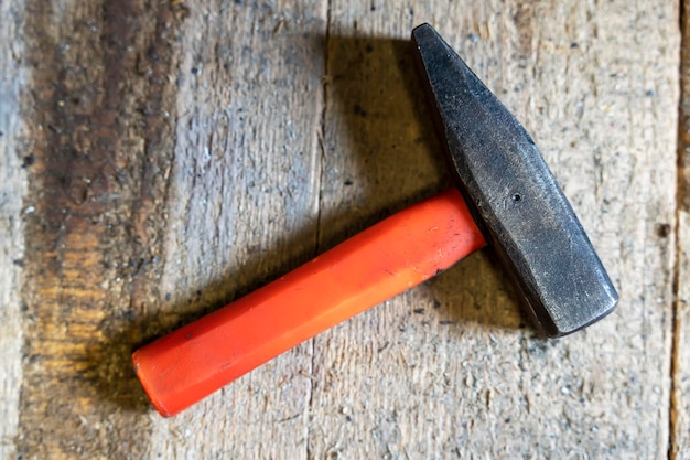 Hammer with a short plastic handle on a wooden background in workshop