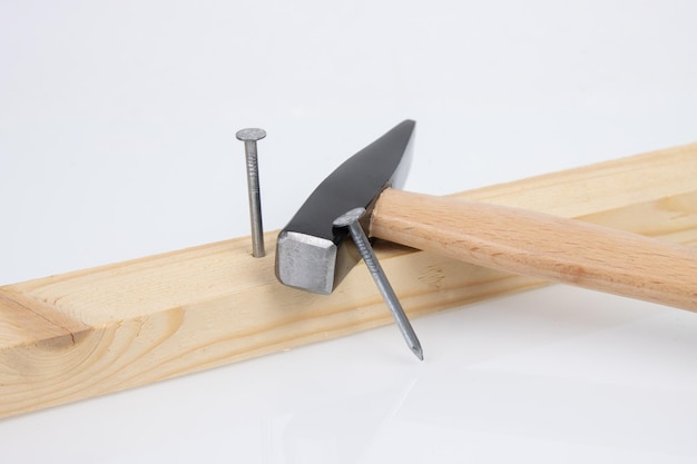 Hammer wooden board and construction nails on white background