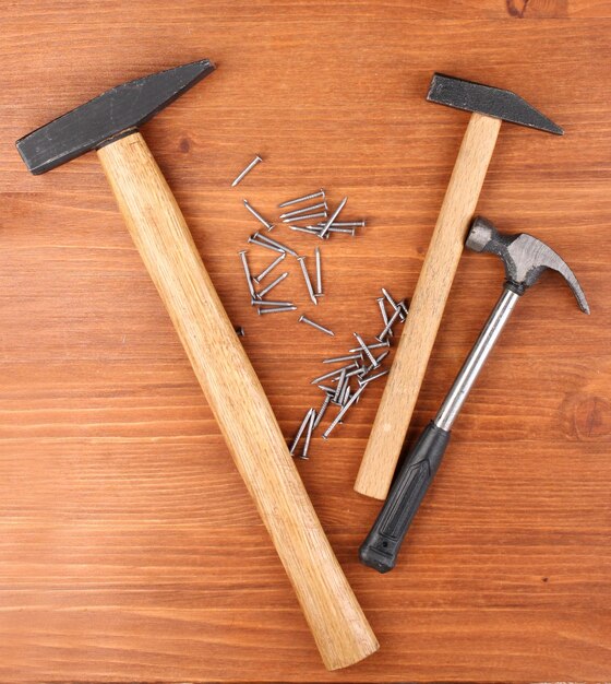 Hammers and metal nails on wooden background