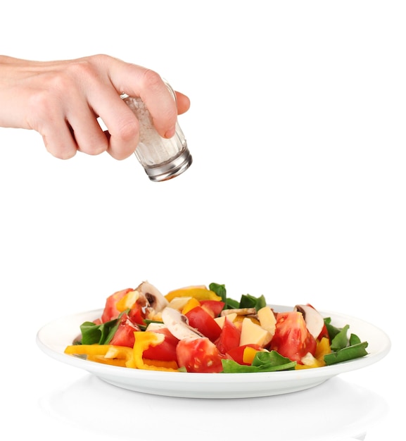 Hand adding salt using salt shaker isolated on white