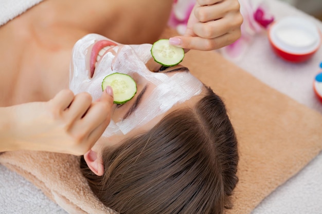 Hand applying nourishing mask on female face in spa salon