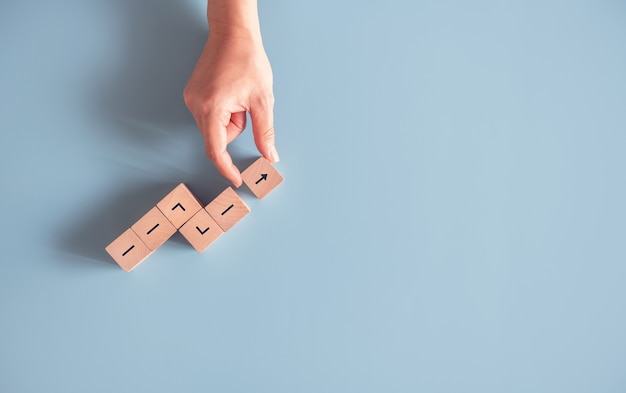 Hand arranging wood block stacking as growth success.