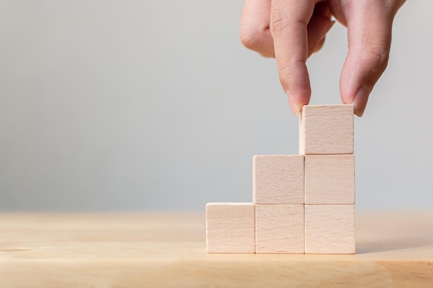 Hand arranging wood block stacking as step stair on top Business concept for growth success process