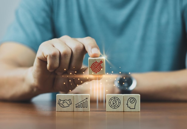 Hand arranging wood block stacking with business strategy and Action plantargeting the business