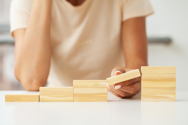 Hand arranging wood cube stacking as stair step shape