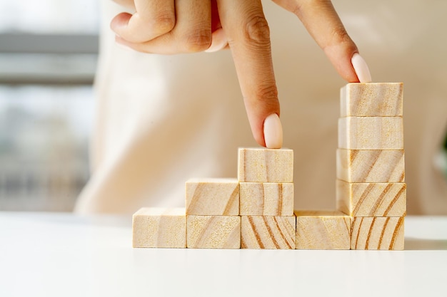 Hand arranging wood cube stacking as stair step shape