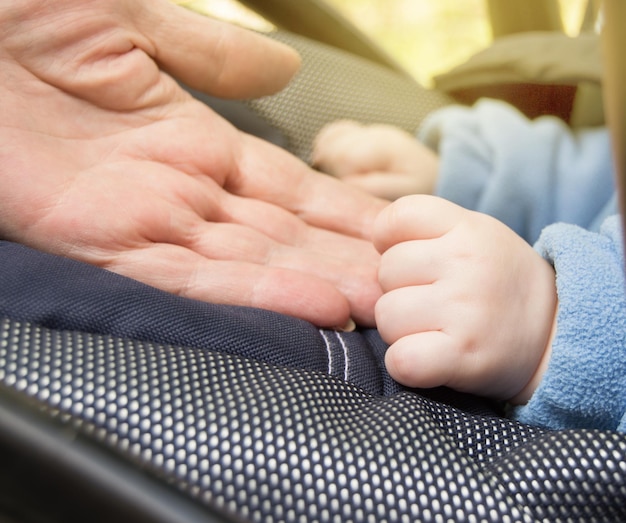 Hand baby and elderly women grandmothers selective focus selective focus baby is in the stroller while walking outdoors closeup