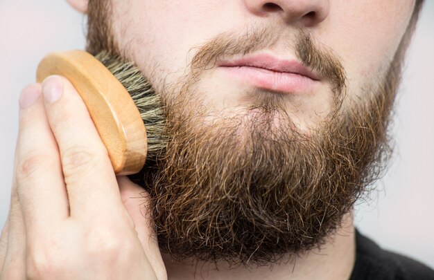 Photo hand of barber brushing beard. barbershop customer,front view. beard grooming tips for beginners.