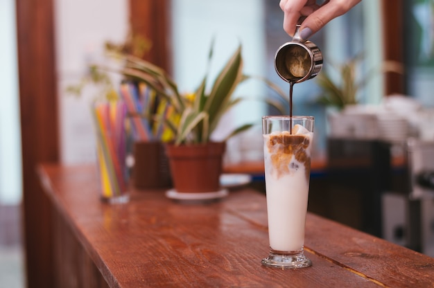 Hand of barista making latte or cappuccino coffee pouring milk 