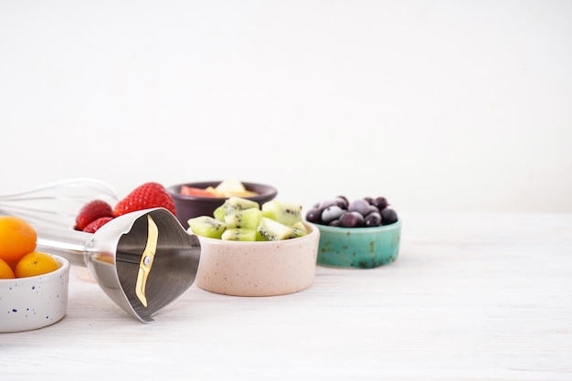 Hand blender and accessories with sliced fruit on a wooden background, close-up.