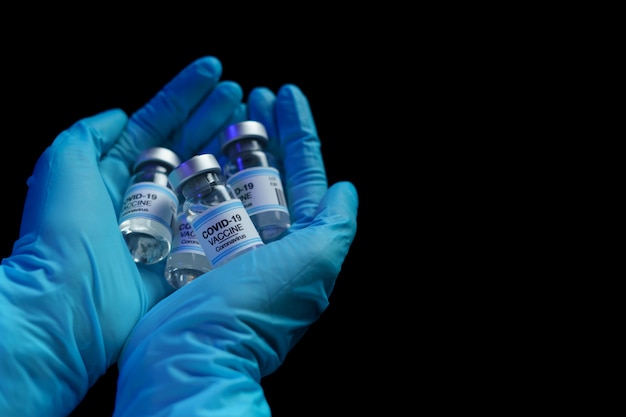 Hand in blue glove holding vaccine and syringe injection for prevention, immunization and treatment from corona virus infection.