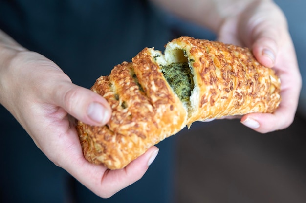 A hand breaks a spinach bun in half closeup Eating quick snacks