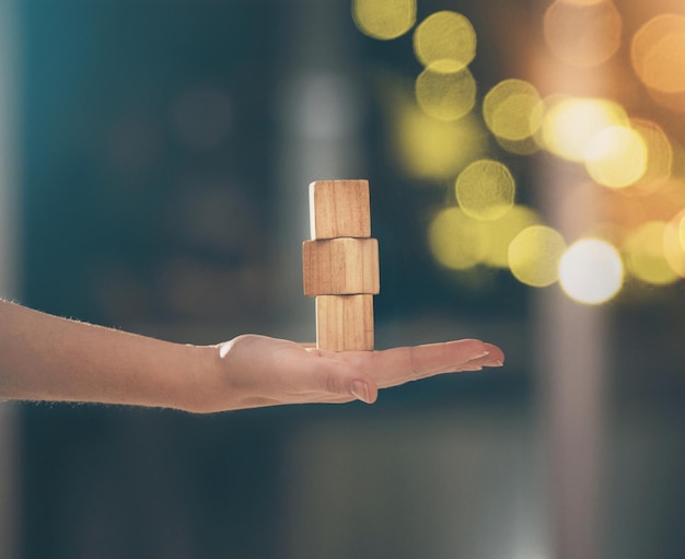 Hand building blocks and balance with a business woman holding wood for growth on a blurred background Investment portfolio and stack with the foundation of a company built on financial stability