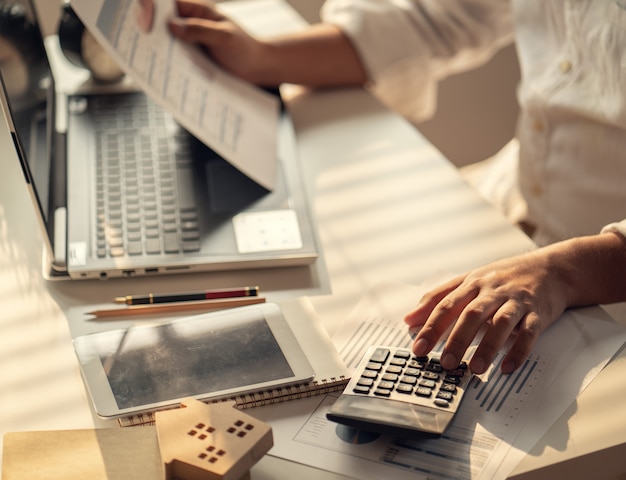 Hand of Business people calculating interest, taxes and profits to invest in real estate and home buying