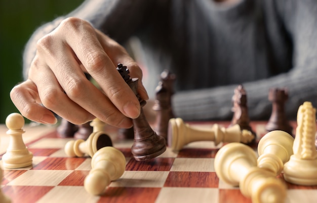 Hand of business woman playing chess for game in competition success