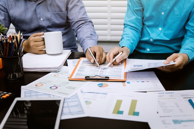 Hand of businessman holding the pen point to the graph information during discussion at meeting