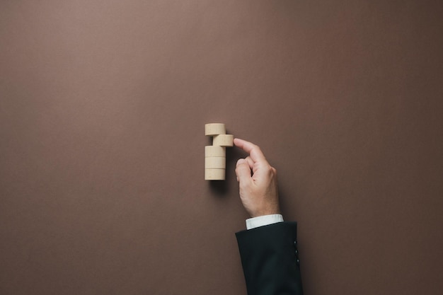 Hand of a businessman pushing a blank wooden cut circle into a stack of them