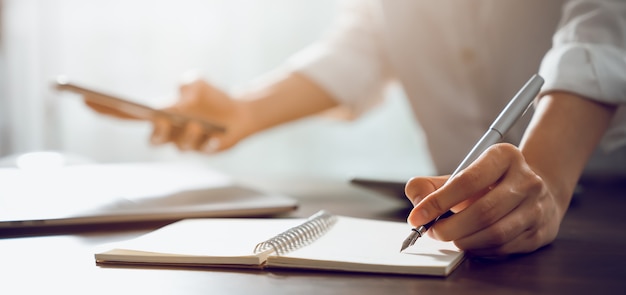 Hand of a businesswoman writing in a notepad