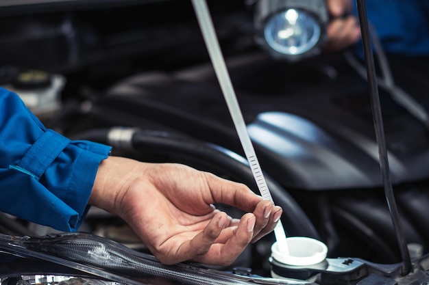 Hand of car mechanic checking on oil level at the auto garage shop