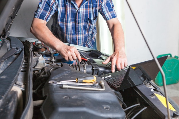 The hand of a car repairman with a laptop. Car repair in an auto repair shop.