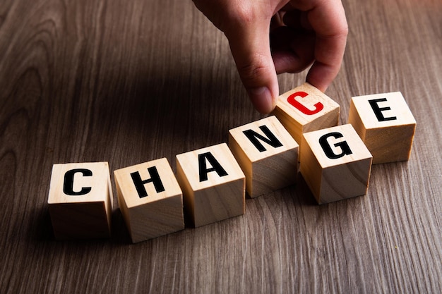 Hand changing wooden cube with word change to chance