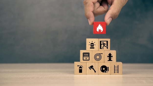 Hand choose wooden block stack with fire icon with door exit with fire extinguisher and emergency prevent protection symbol for safety