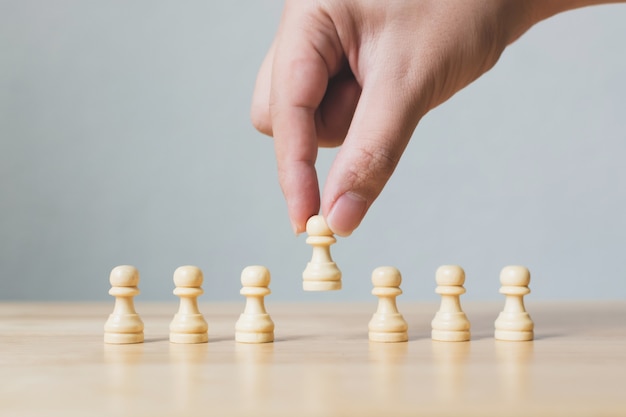 Hand chooses a wooden chess standing out from the crowd