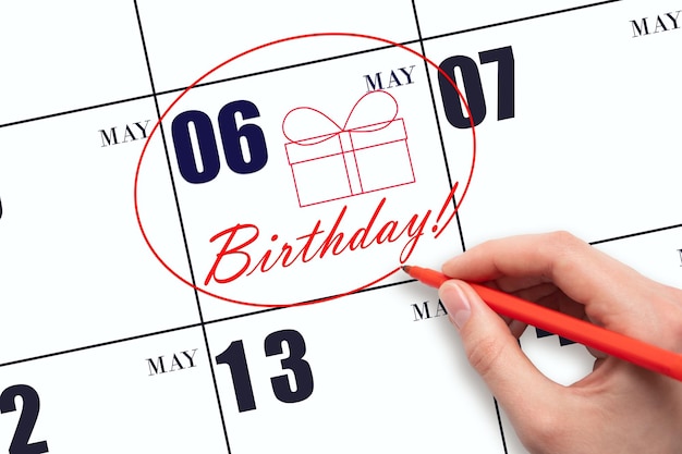 The hand circles the date on the calendar 6 May draws a gift box and writes the text Birthday Holiday