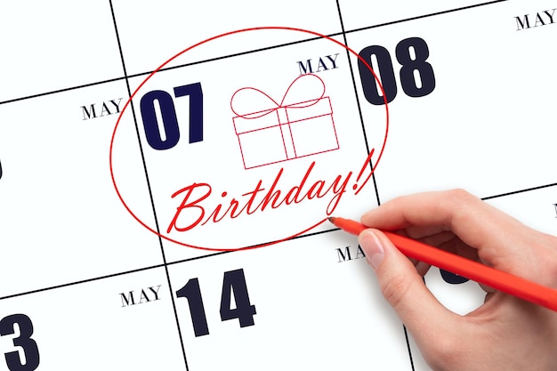 The hand circles the date on the calendar 7 May draws a gift box and writes the text Birthday Holiday