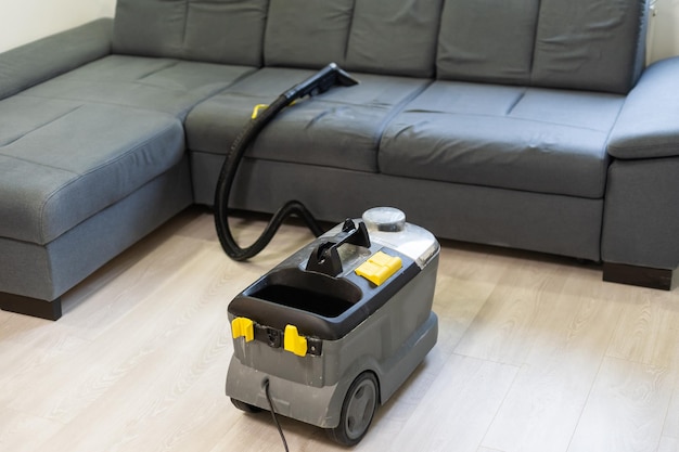 Hand cleaning a sofa with a steam cleaner, Home cleaning concept.