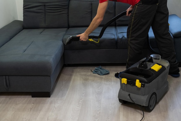 Hand cleaning a sofa with a steam cleaner, Home cleaning concept.