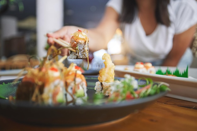 Hand closeup and chopsticks in sushi restaurant for diet fine dining and party with catering platter Person healthy fish and salmon with culture traditional or fast food in diner bar or store