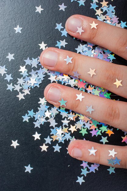 Hand on colorful confetti stars on a dark color background