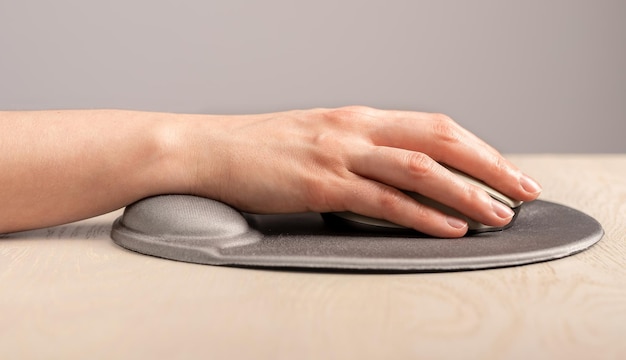 Hand on computer mouse on pad with wrist rest support