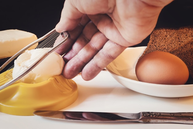 Hand controls an egg cutter on the background of products for making a sandwich