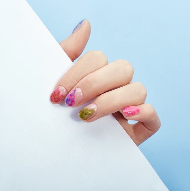 Hand cosmetics nails coloring and care, professional manicure and care product. Hand lying on a colored paper background