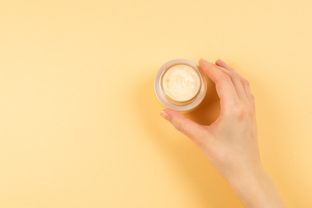 Hand cream and woman hands on a beige background