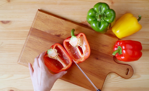 Hand Cutting Red Bell Pepper on Wooden Cutting Board