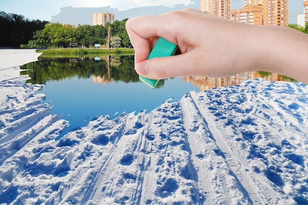 Hand deletes winter snow field by rubber eraser