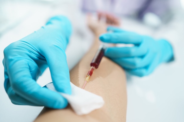 Hand of doctor in blue gloves taking blood sample from a patient.