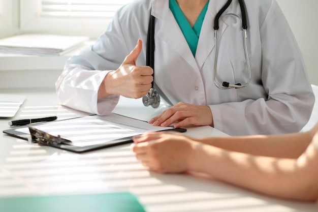 Hand of doctor  reassuring her female patient and showing ok sign. Medical ethics and trust concept