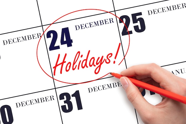 Hand drawing a red circle and writing the text Holidays on the calendar date 24 December Important date