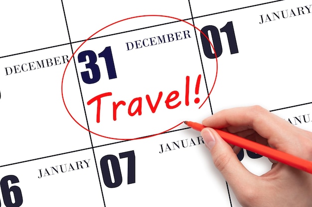 Hand drawing a red circle and writing the text TRAVEL on the calendar date 31 December Travel planning