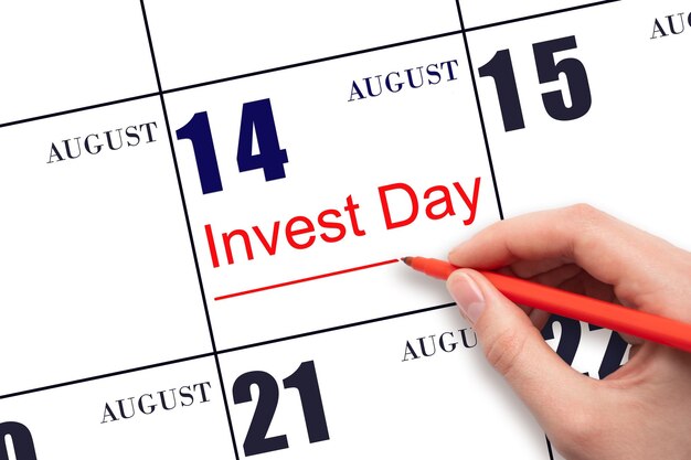 Hand drawing red line and writing the text Invest Day on calendar date August 14 Business and financial concept