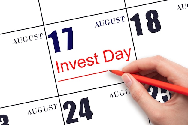 Hand drawing red line and writing the text Invest Day on calendar date August 17 Business and financial concept