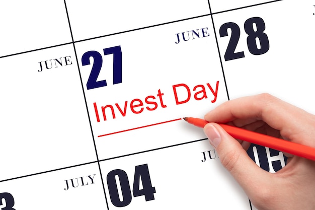 Hand drawing red line and writing the text Invest Day on calendar date June 27 Business and financial concept